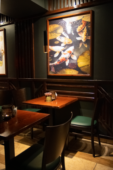 Ein Tisch mit Stühlen in einem restaurantartigen Raum, dekoriert mit einem Kunstwerk.