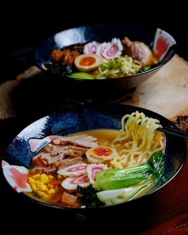 Eine Schüssel Ramen mit Brühe, Nudeln, Gemüse, Eiern und verschiedenen Belägen.