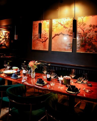 Elegant Restaurant mit einem langen Tisch, dekoriert mit Blumen und Kunstwerken an der Wand.