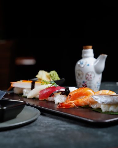 Sushi-Platte mit verschiedenen Sushi-Sorten und einer Sojasaucenkanne.